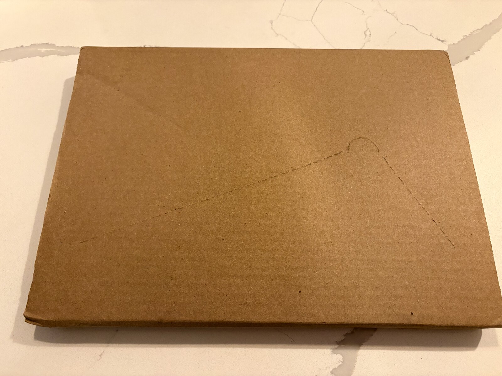 A cardboard package just about the size of the Mellifera book, sitting on a kitchen countertop.